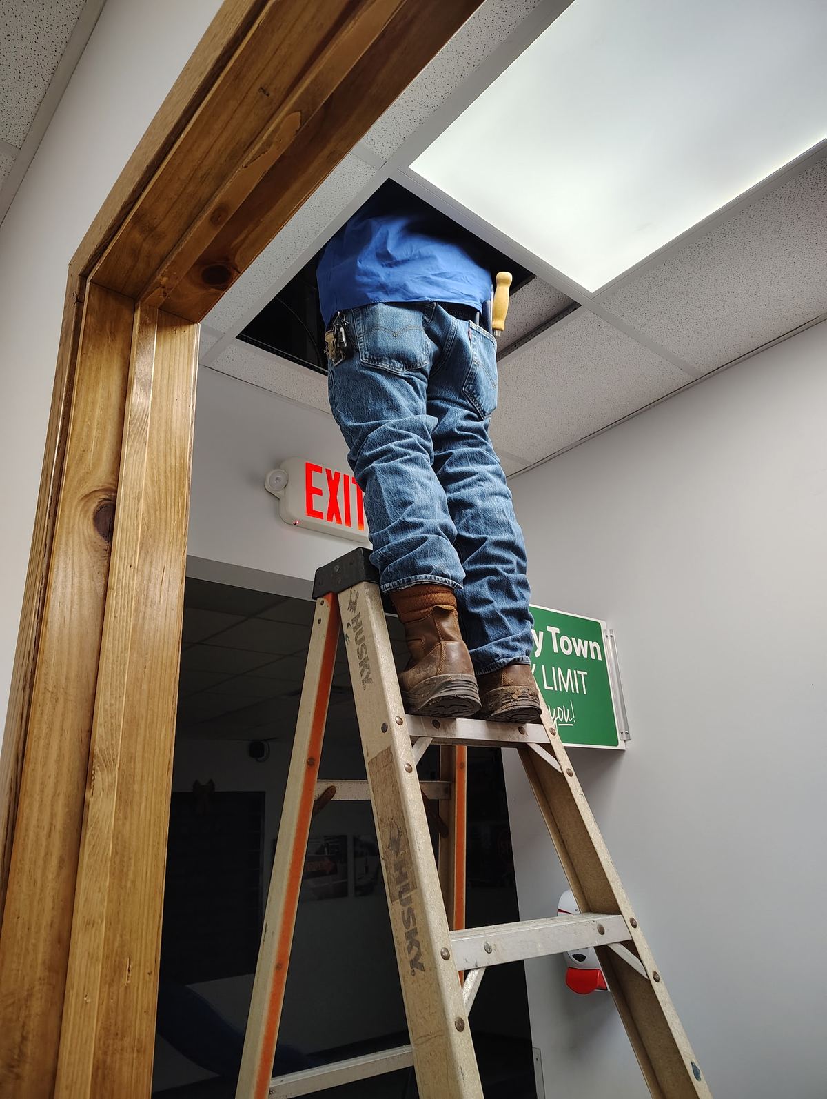 Technician on a ladder working above a commercial drop ceiling