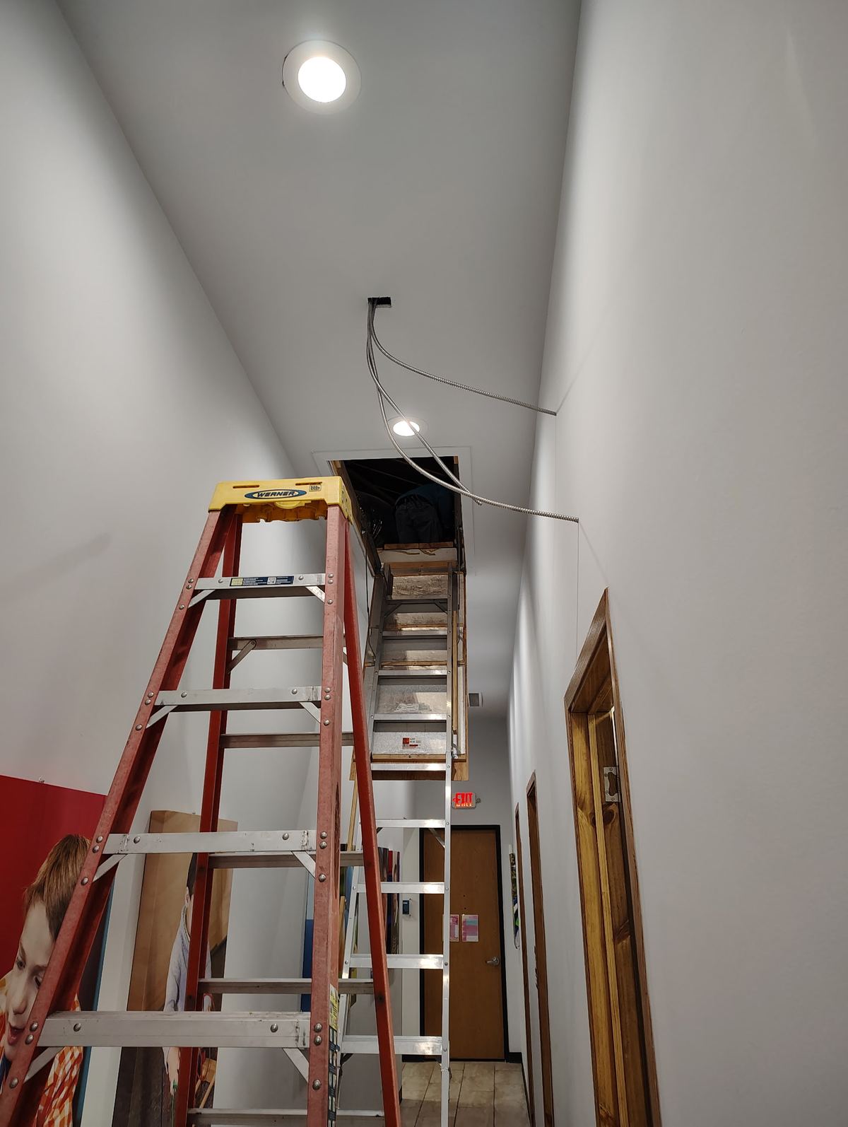 New electrical wiring being run through a finished hallway ceiling
