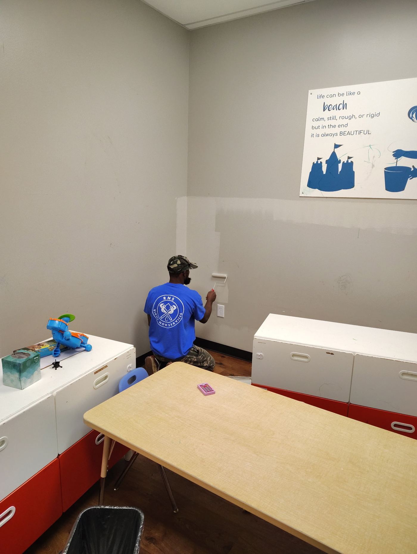 Right Now Services crew member in RNS uniform painting an interior wall during a unit turnover